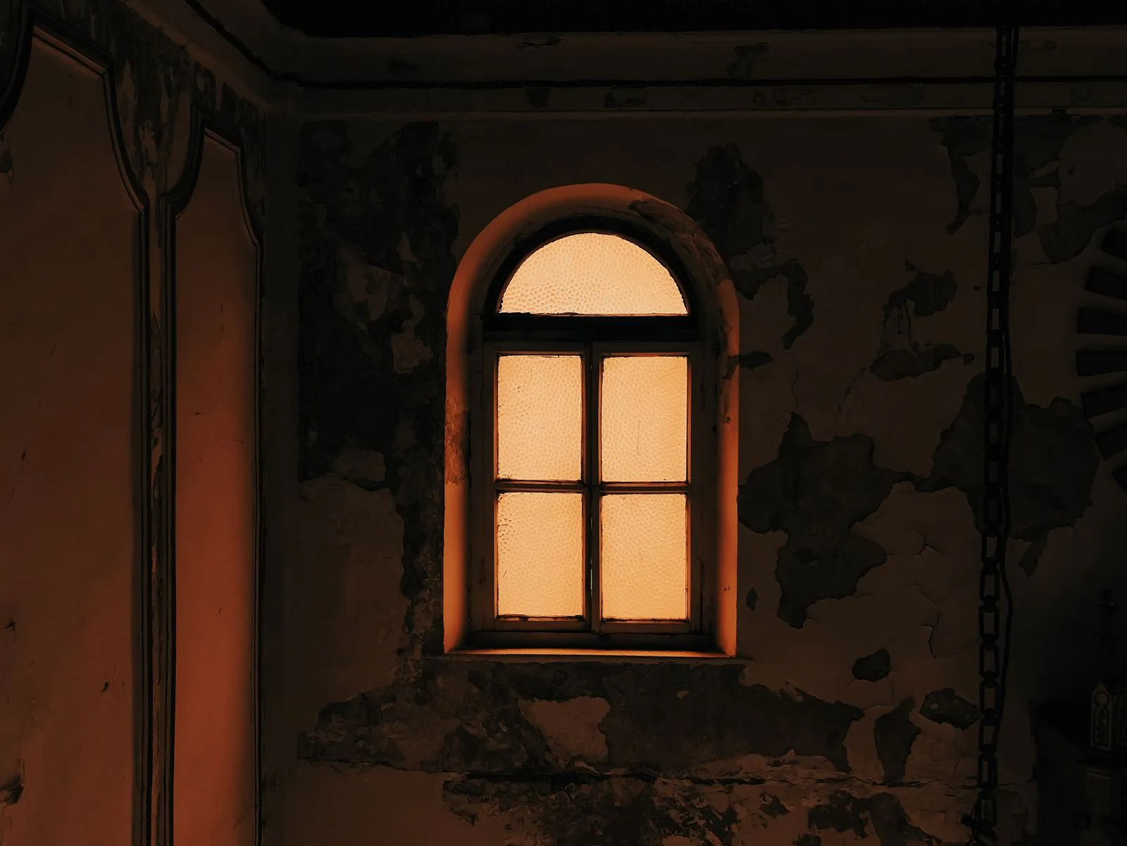 An eerie and neglected window in an old palace casting a mysterious glow.